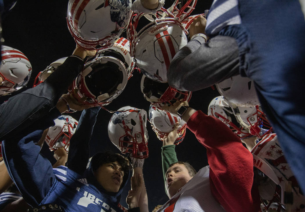 Senior members of the football team bring their helmets together at the end of practice at Libe ...