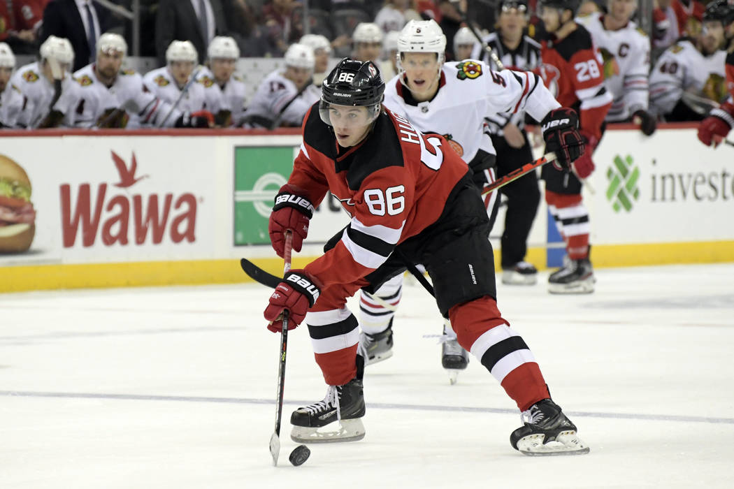 New Jersey Devils center Jack Hughes (86) skates with the puck as he is pursued by Chicago Blac ...