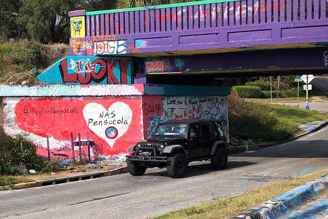 A vehicle drives by a tribute to victims of the Naval Air Station Pensacola that was freshly pa ...