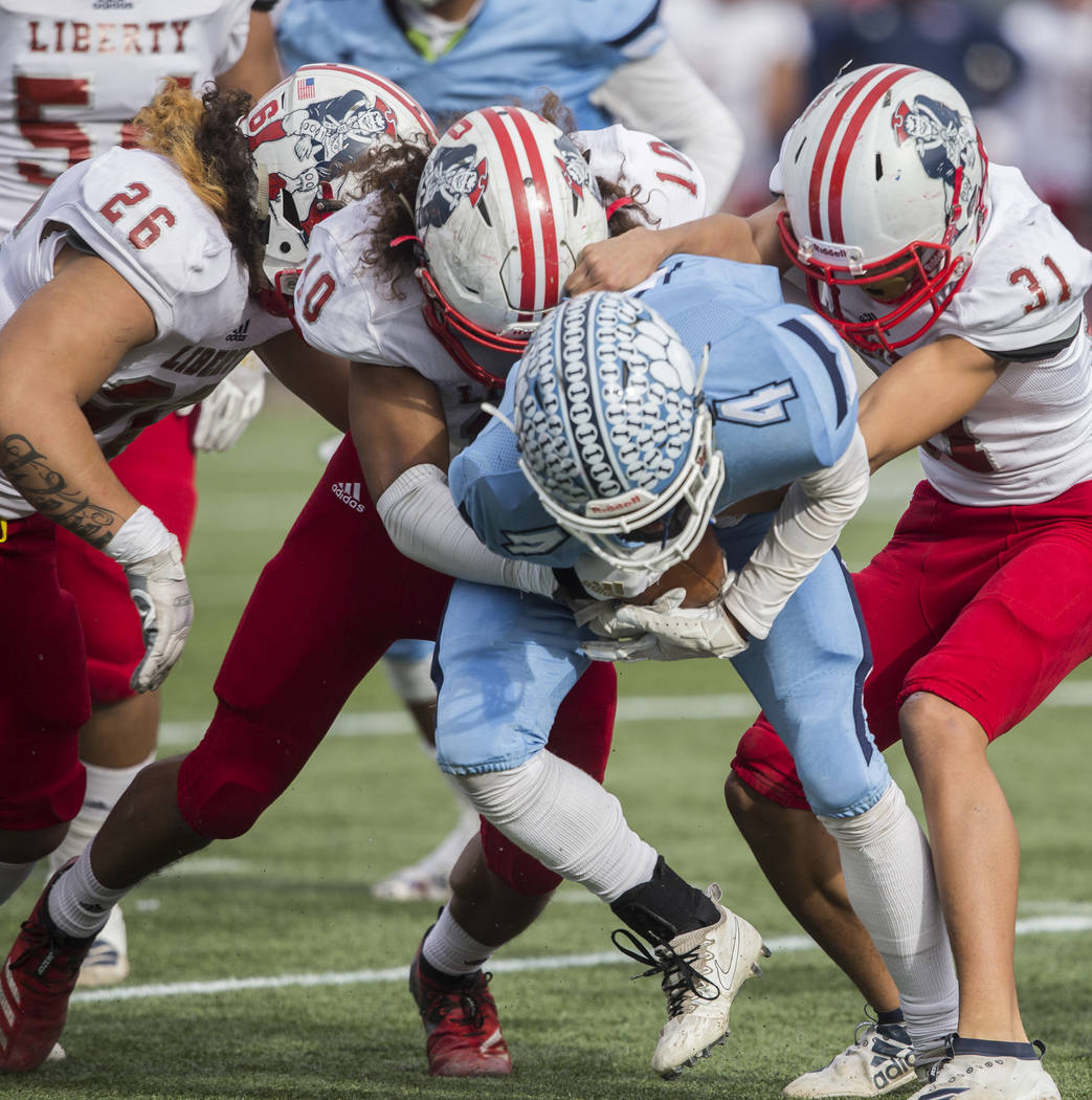 Centennial senior Aaron Johnson (4) is wrapped up in the backfield by Liberty sophomore linebac ...