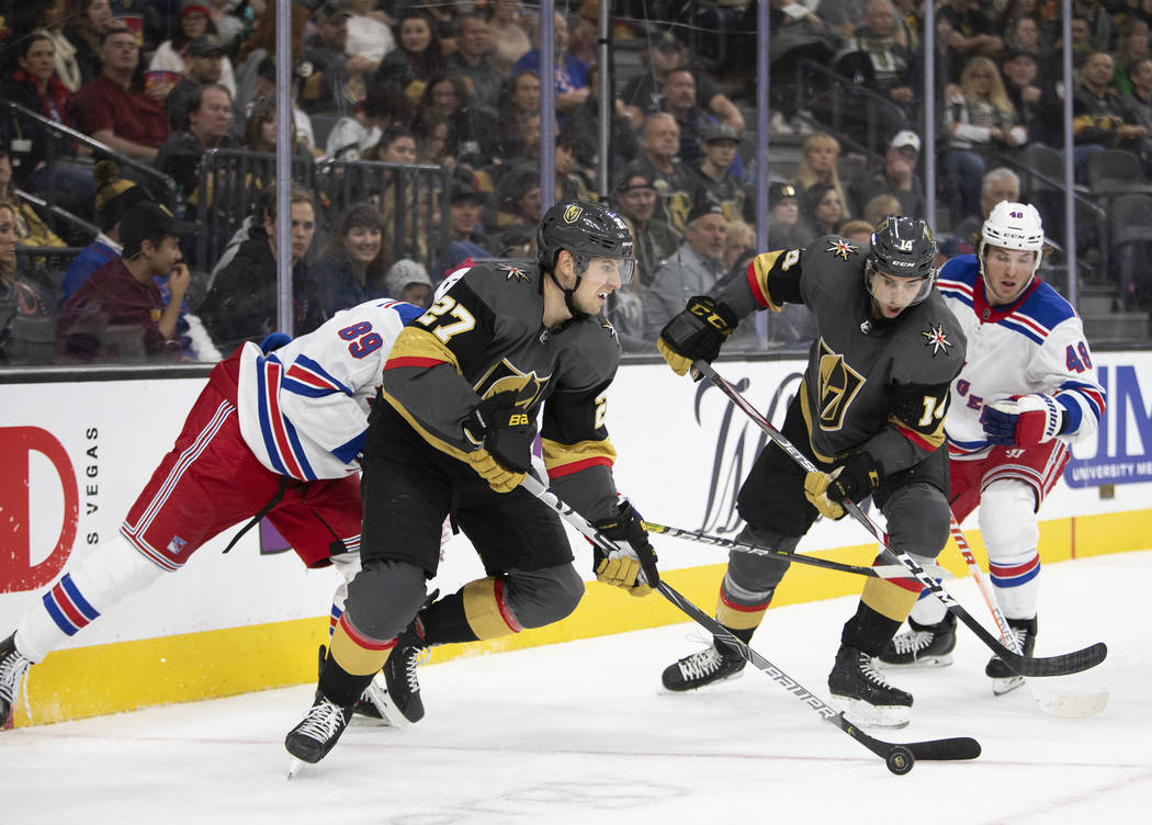 Vegas Golden Knights defenseman Shea Theodore (27) skates with the puck next to Vegas Golden Kn ...