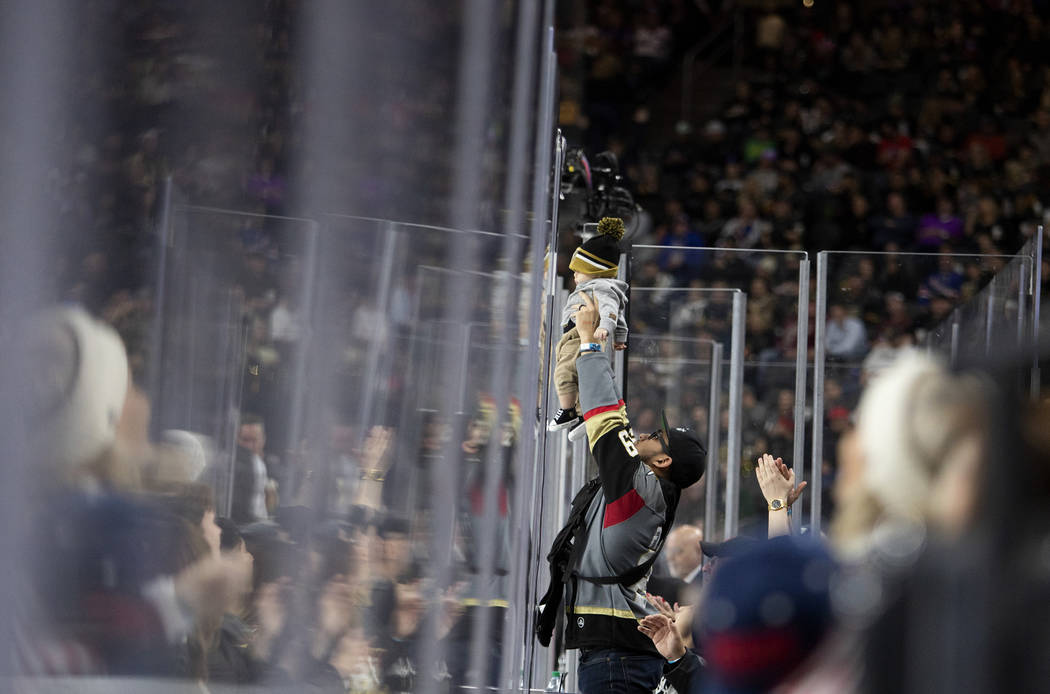 A Golden Knights fan holds up their baby during the third period of the game against the New Yo ...