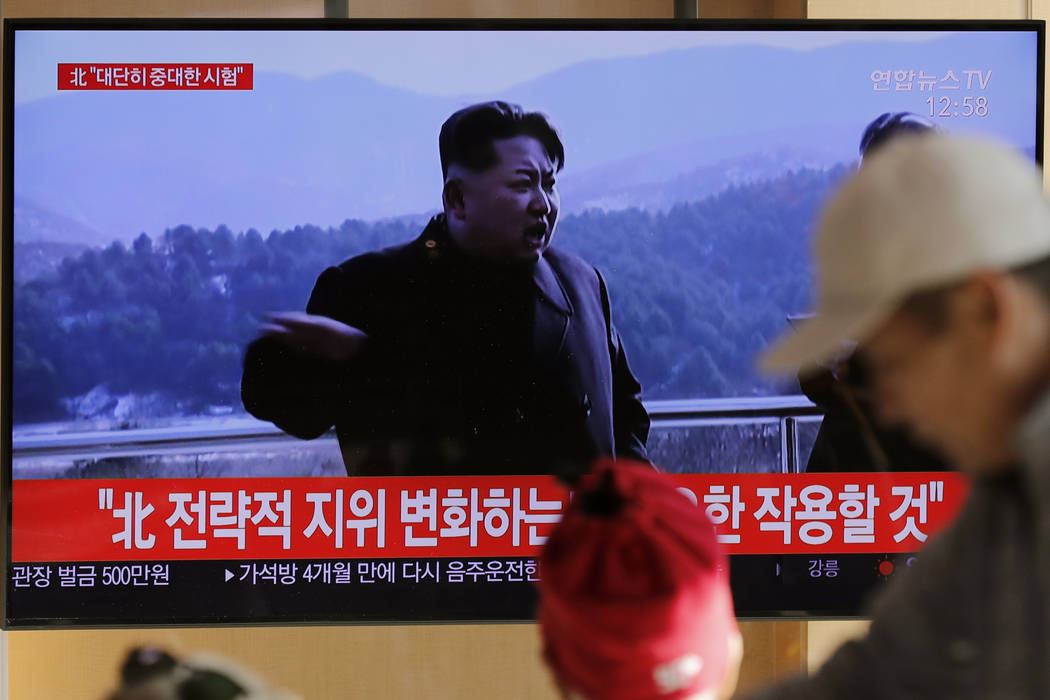 People watch a TV news program reporting North Korea's announcement with a file footage of Nort ...