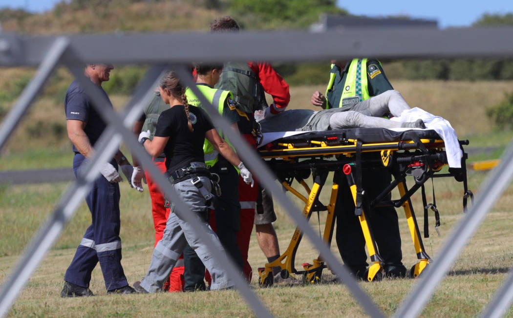 Emergency services attend to an injured person arriving at the Whakatane Airfield after the vol ...