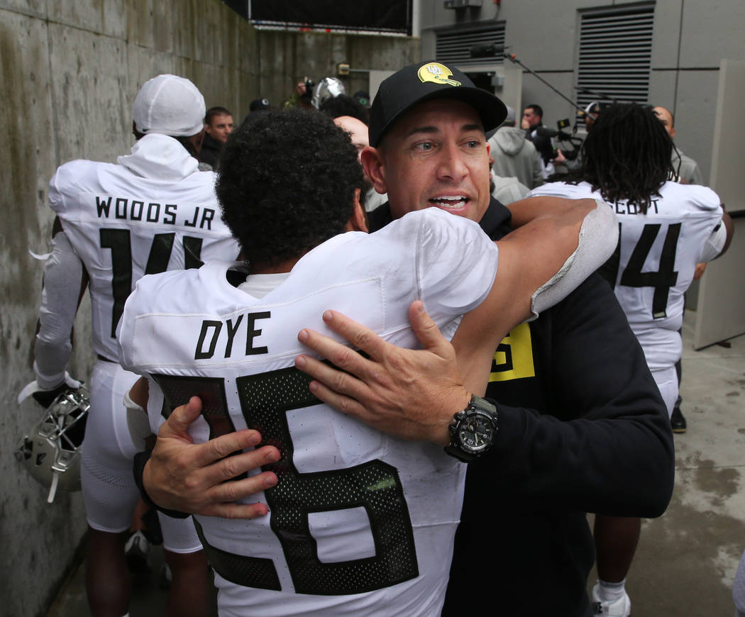 Oregon offensive coach Marcus Arroyo celebrates with Travis Dye after the win over Washington o ...