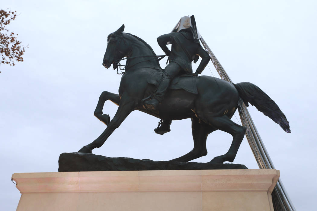 A tarp still covers part of a statue during the unveiling ceremony for a statue titled Rumor's ...