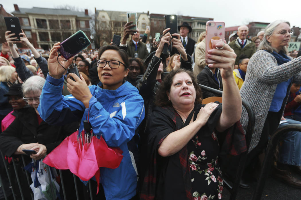 Spectators record a band during the unveiling ceremony for a statue titled Rumor's of War by ar ...