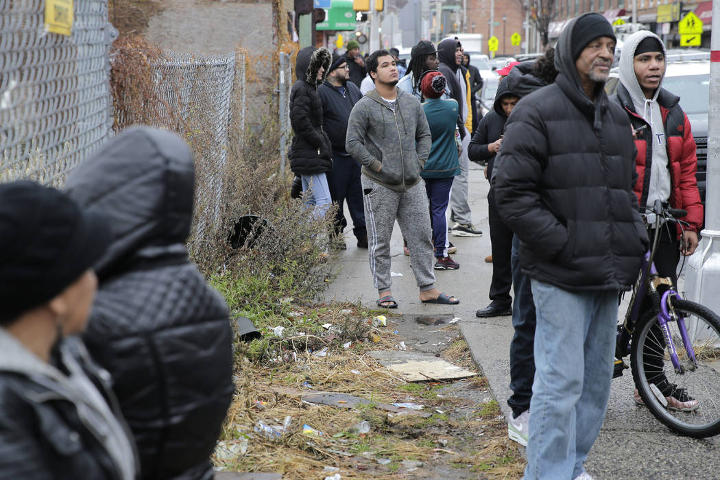 Bystander watch as emergency responders work near the scene of a shooting in Jersey City, N.J., ...