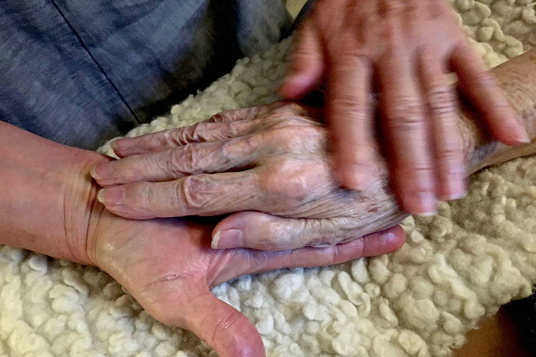 In this 2016 photo provided by Thomas Marrinson, Allison Beach holds the hand of her ailing mot ...