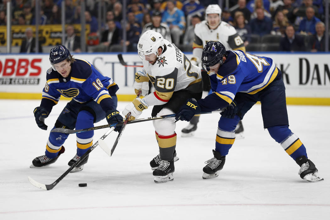 Vegas Golden Knights' Chandler Stephenson (20) reaches for a puck between St. Louis Blues' Robe ...