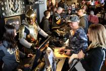 The Golden Knight steps in to help Vivika Kim, left, ring up Mike and Stephanie Ibasco of Mount ...