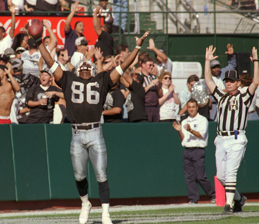 Oakland Raiders Raghib "Rocket" Ismail raises his arms in the end zone after catching a 44-yard ...