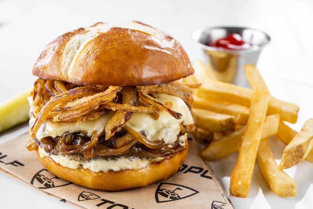 The French Onion Burger at Topgolf at MGM Grand is a juicy, 7-ounce burger perched on a pretzel ...
