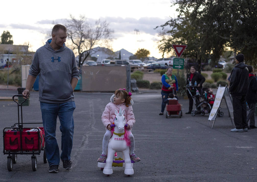Corey Conrad, left, walks into WinterFest as his daughter Dalya, 4, right, rides a unicorn into ...