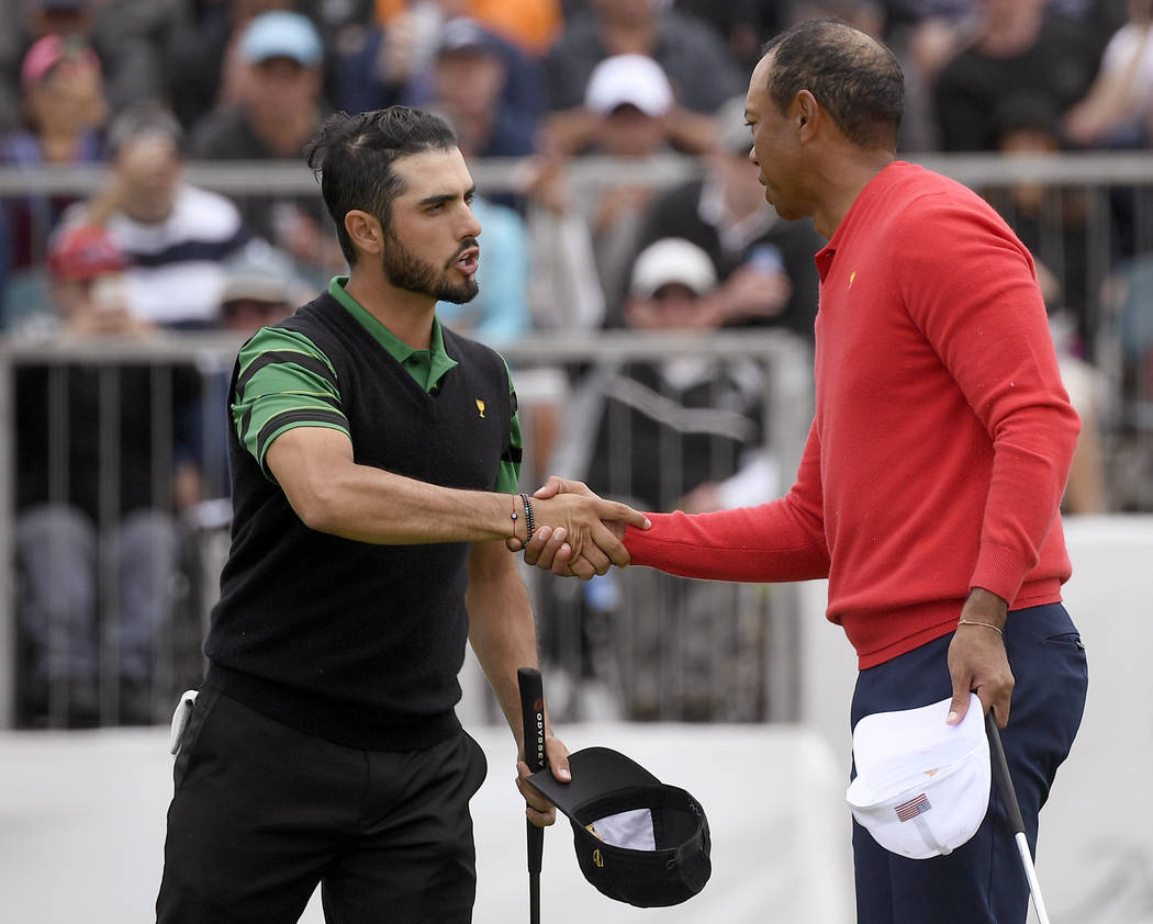 U.S. team player and captain Tiger Woods, right, shakes hands with International team player Ab ...