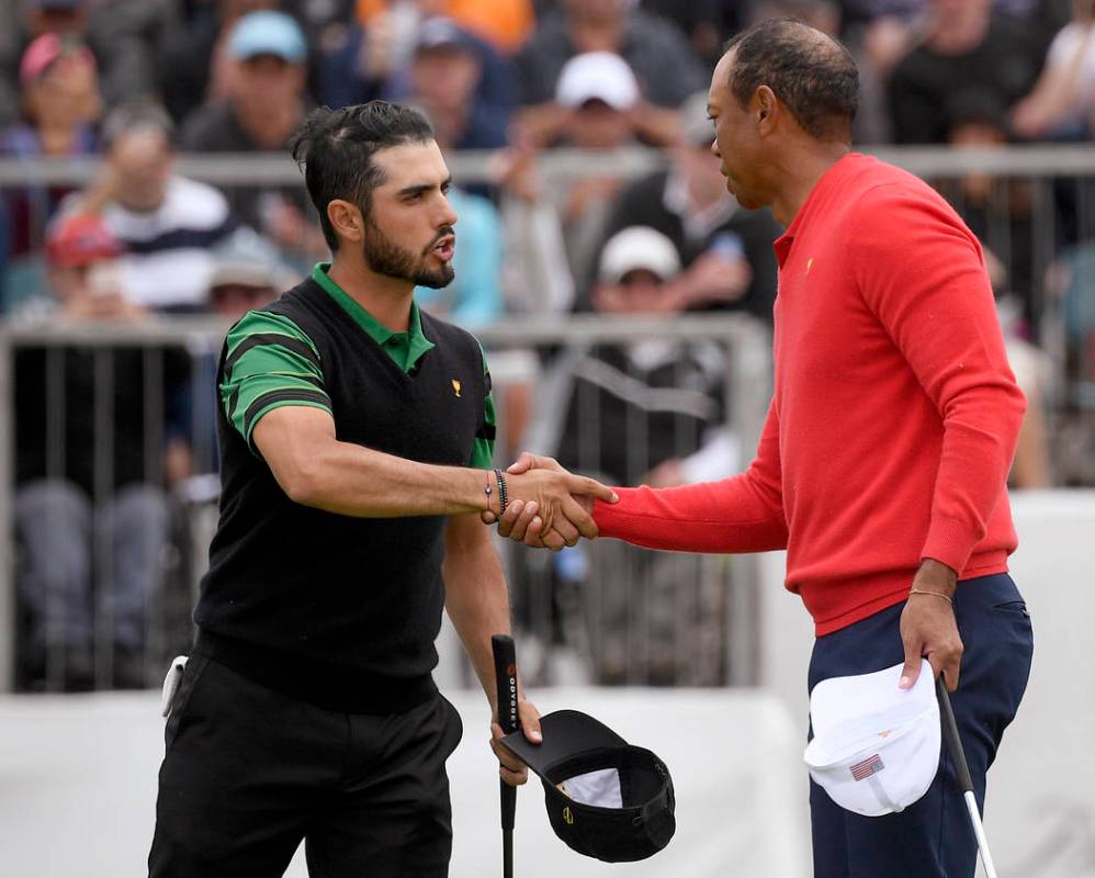 U.S. team player and captain Tiger Woods, right, shakes hands with International team player Ab ...
