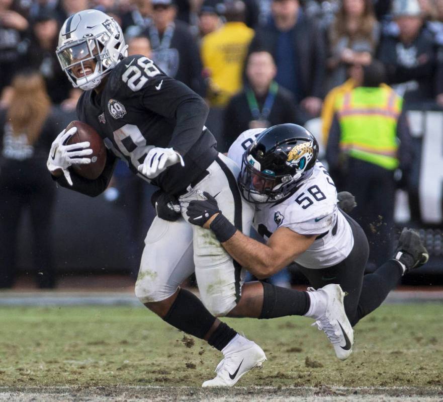 Oakland Raiders running back Josh Jacobs (28) drags Jacksonville Jaguars outside linebacker Aus ...