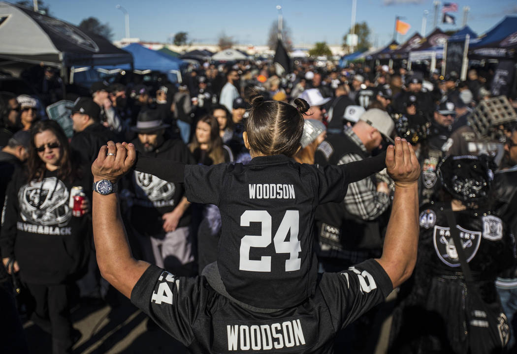 Roman Arroyo holds his daughter Emma, 3, at a tailgate outside the Oakland Coliseum before the ...