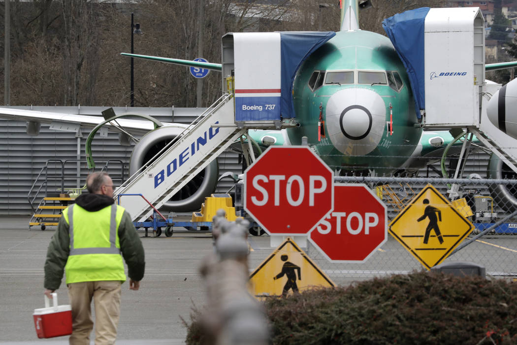 A Boeing worker walks in view of a 737 MAX jet Monday, Dec. 16, 2019, in Renton, Wash. Shares o ...