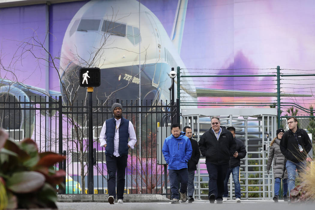 Boeing workers exit the plant in front of a giant mural of a jet on the side of the manufacturi ...