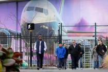 Boeing workers exit the plant in front of a giant mural of a jet on the side of the manufacturi ...