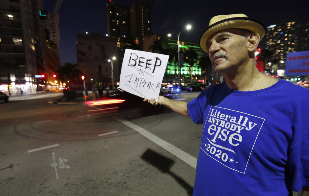 Neil Bersin holds up a sign in favor of the impeachment of President Donald Trump as he joined ...