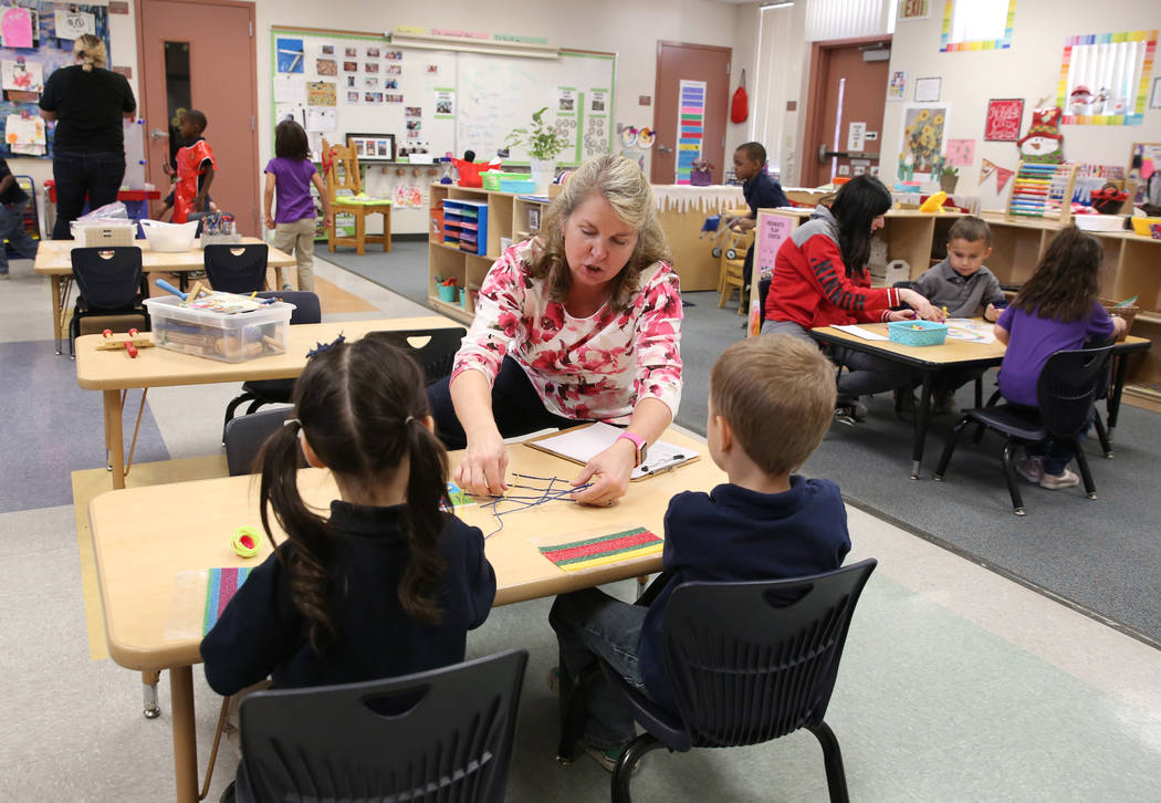 Pre-kindergarten teachers, Leslie Gallant, center, and Autumn Naegle, right, help students work ...