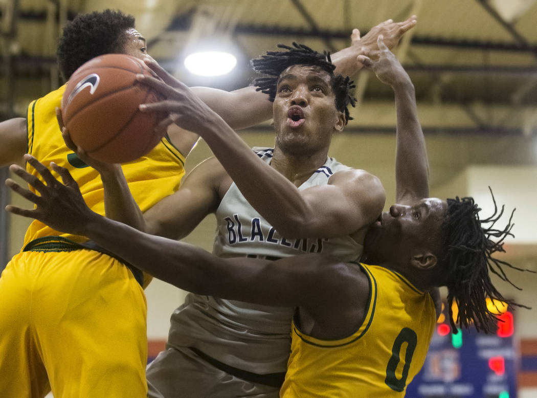 Sierra Canyon senior forward Terren Frank (15) splits Oak Ridge defenders Michael James (0) and ...