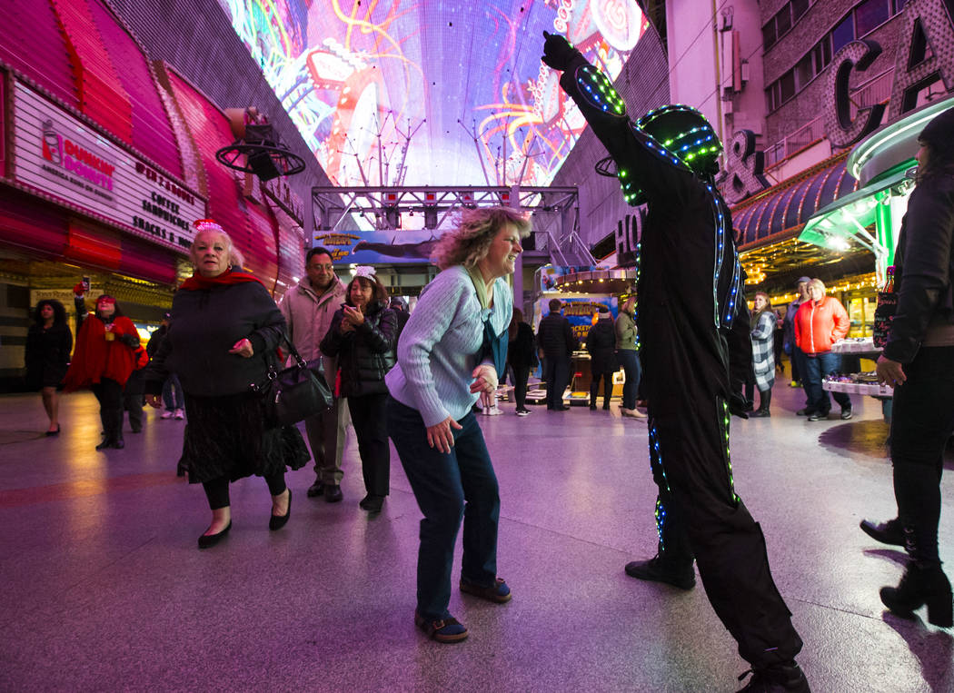 Karen Johnston of Colo., center, dances with a costumed entertainer as New Year's Eve revelers ...