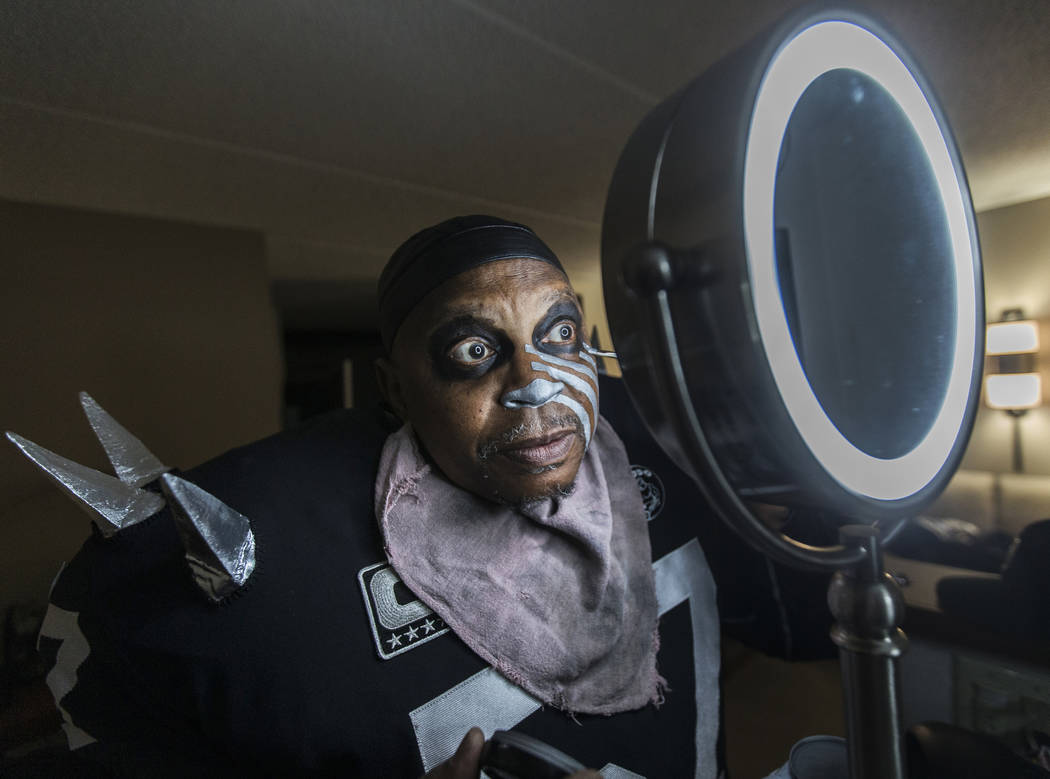 Raiders super fan Wayne Mabry, known as "Violator," applies makeup in his hotel room ...