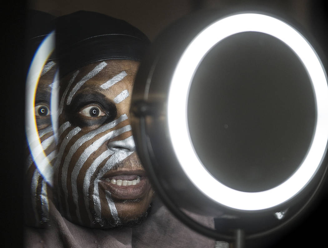 Raiders super fan Wayne Mabry, known as "Violator," applies makeup in his hotel room ...