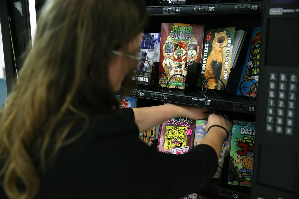 Assistance Principal Michelle Thom organizes books inside a book vending machine at Frank Kim E ...