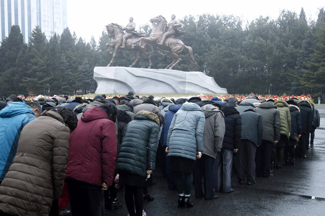 North Koreans bows in front of the bronze statues of their late leaders Kim Il Sung, left, and ...