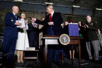 President Donald Trump hands a pen to Gen. Jay Raymond, after signing the National Defense Auth ...