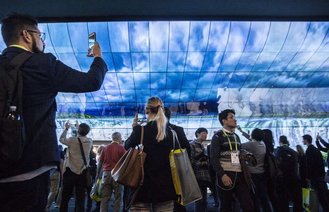 Convention goers watch a huge LG visual display in the North Hall of the Las Vegas Convention C ...