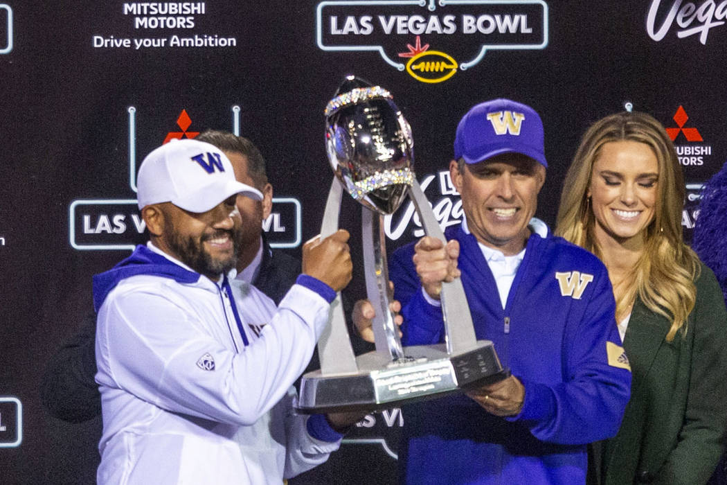 Washington Huskies head coach Chris Petersen, center, and incoming head coach Jimmy Lake, left, ...