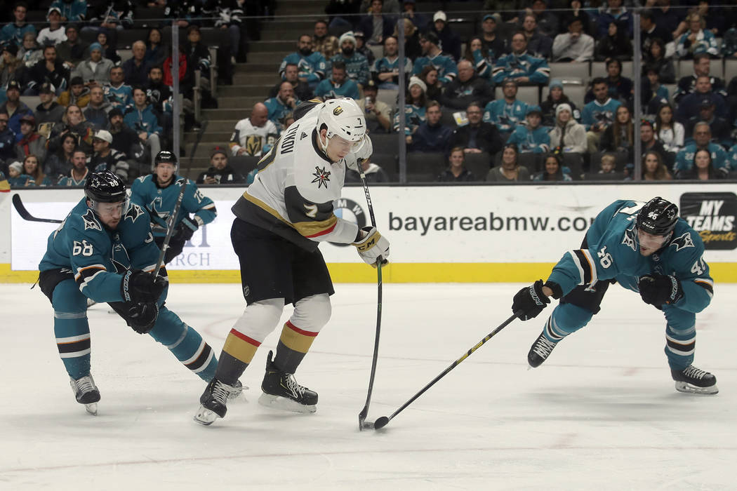 Vegas Golden Knights' Valentin Zykov, center, hits the puck between San Jose Sharks center Melk ...