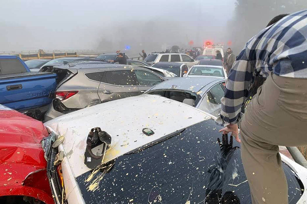 A person climbs over crashed cars at the scene of a multi-vehicle pileup on Interstate 64 in Yo ...
