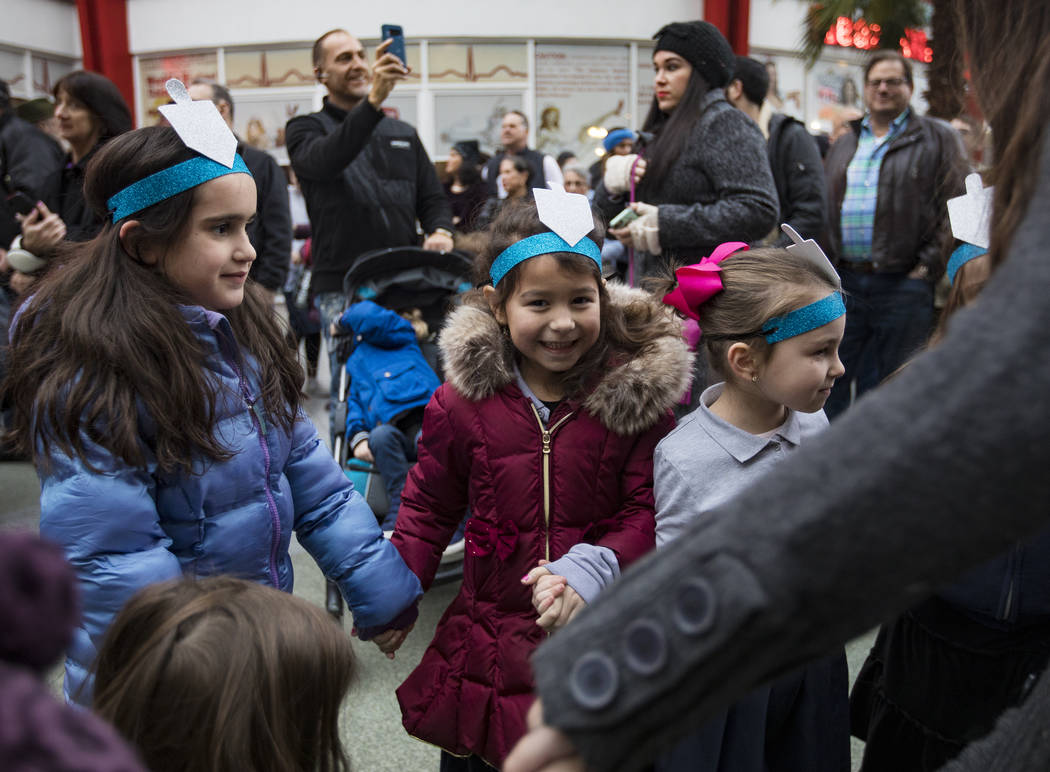 Henny Attal, 6, from left, dances with Roza Metal, 6, and Yehudis Markel, 6, at a menorah light ...