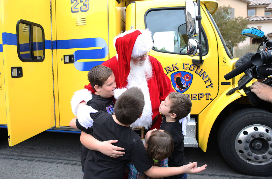 Ethan Runyan, 10, left, and his siblings Erick Jr., 8, center, Aria, 4, and Ein, 6, hug Santa o ...