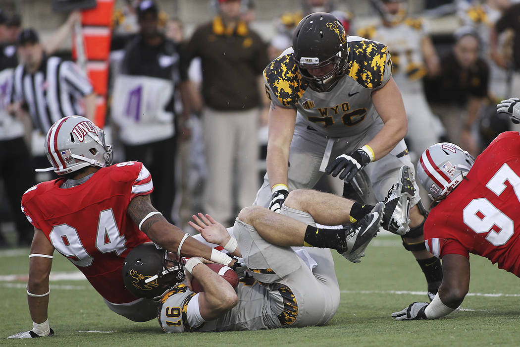 UNLV's Jeremiah Valoaga (94) and Mark Garrick (97) sack Wyoming quarterback Brett Smith (16) a ...