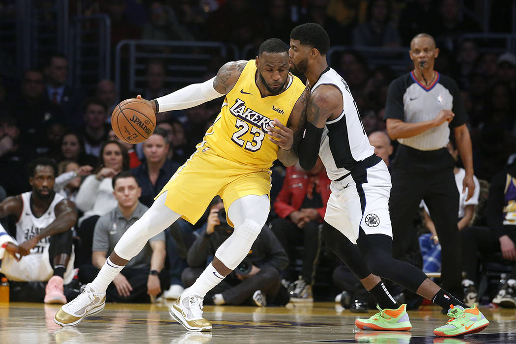Los Angeles Lakers' LeBron James (23) is defended by Los Angeles Clippers' Paul George during t ...