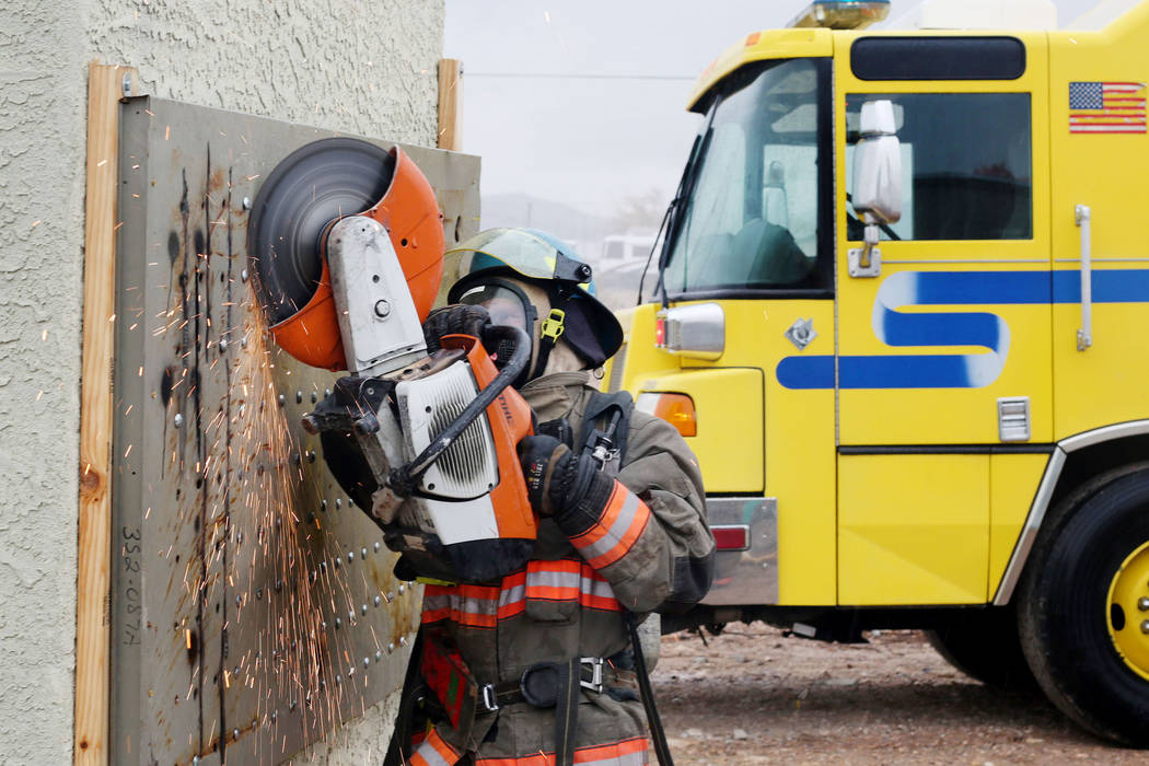 A recruit cuts through a wall during a forcible entry drill during the Clark County Fire Depart ...