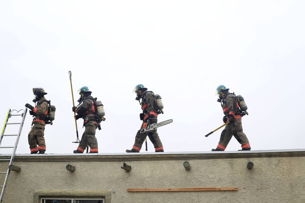 Recruits partake in the Clark County Fire Department's live fire training on a house located at ...