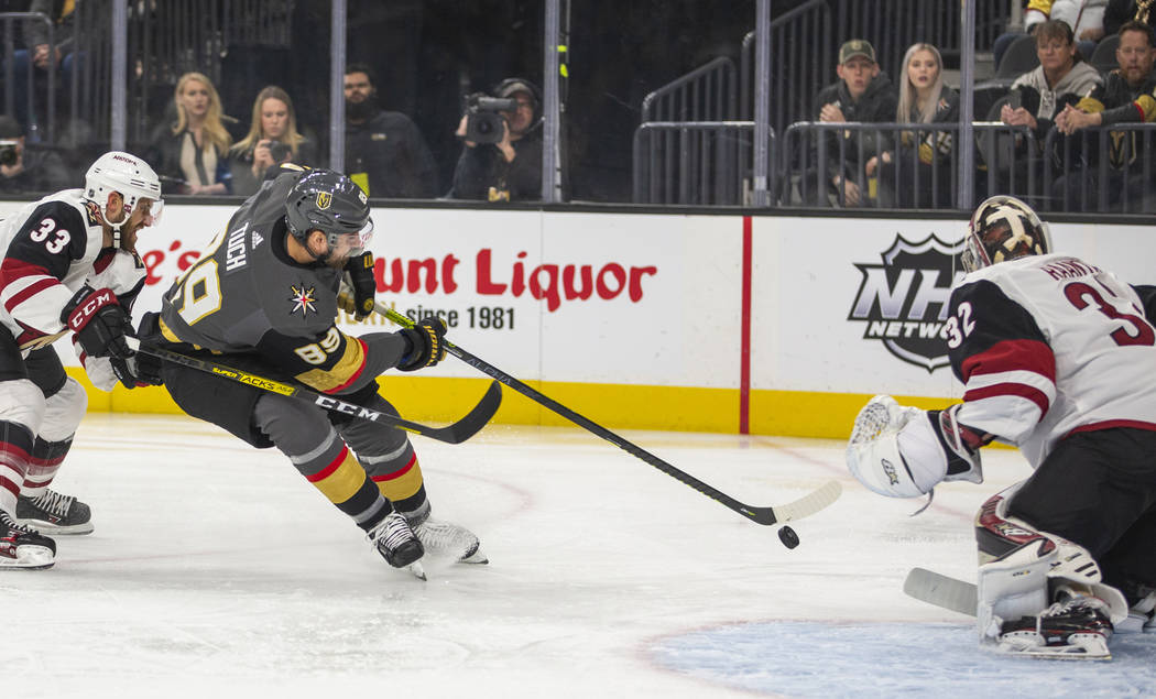 Vegas Golden Knights right wing Alex Tuch (89, center) looks to shoot on Arizona Coyotes goalte ...