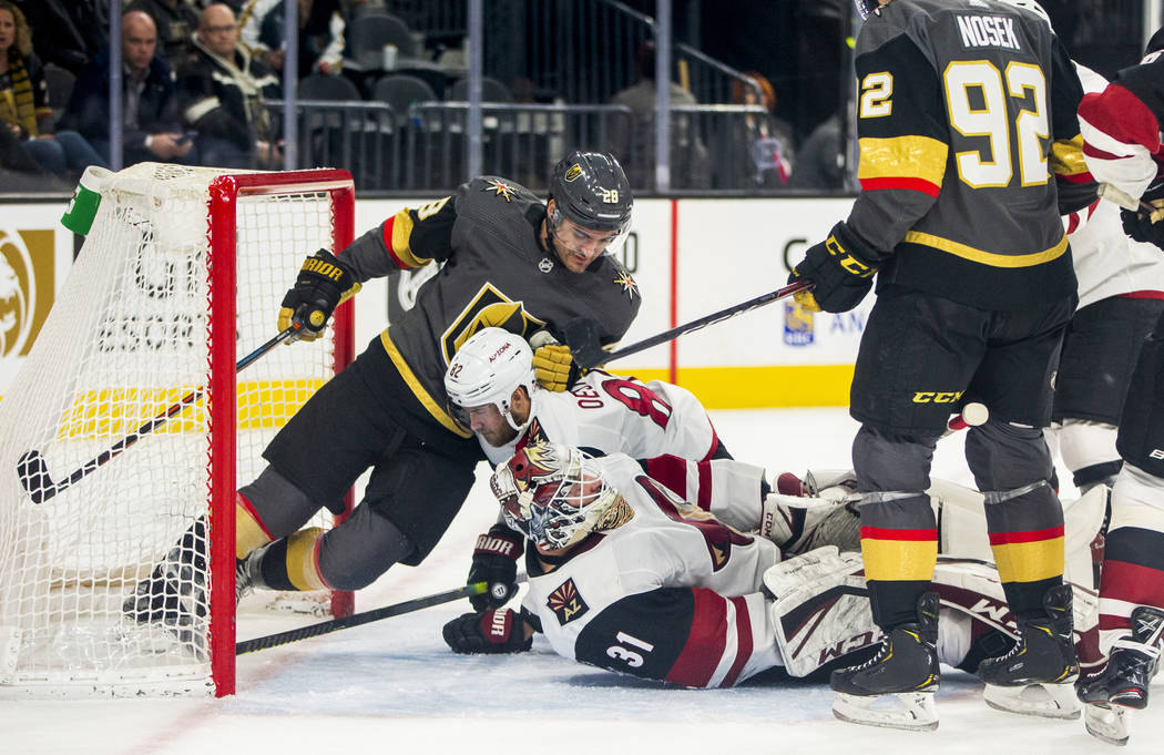 Vegas Golden Knights left wing William Carrier (28, left) falls atop of Arizona Coyotes defense ...