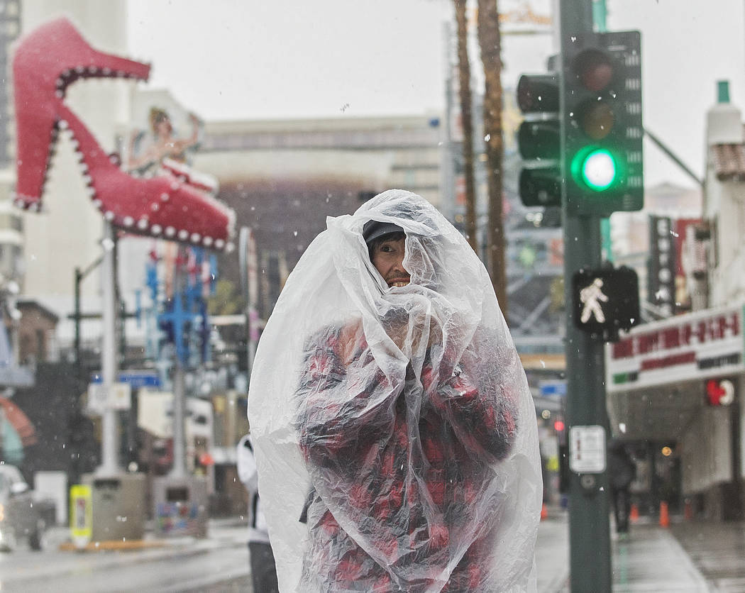 Bruce Outwater tries to stay dry while waking on Fremont Street in the early morning snow in Do ...