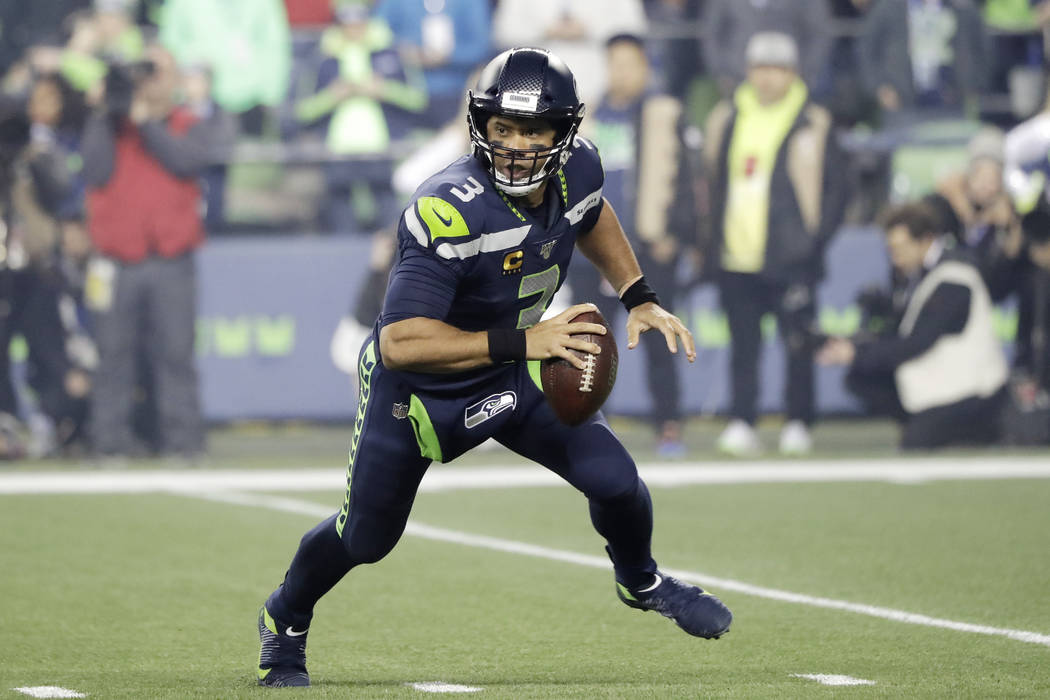 Seattle Seahawks quarterback Russell Wilson looks for room to pass against the San Francisco 49 ...