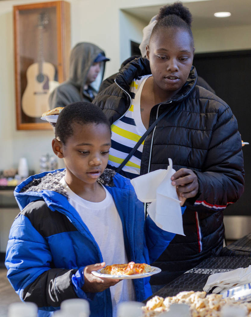 Andru Roach, 7, and Dayshena Thomas receive a meal during a luncheon for the tenants of the Alp ...