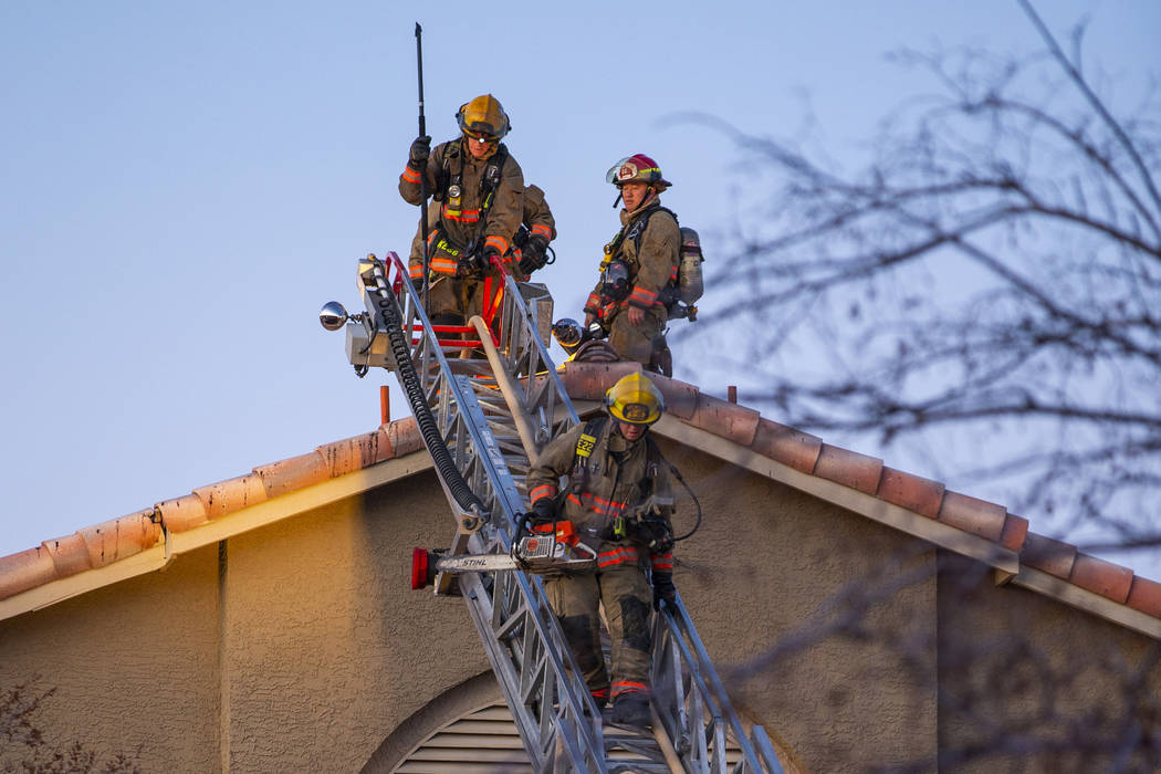 Firefighters with the Clark County Fire Department descend the roof of an apartment at the Glor ...